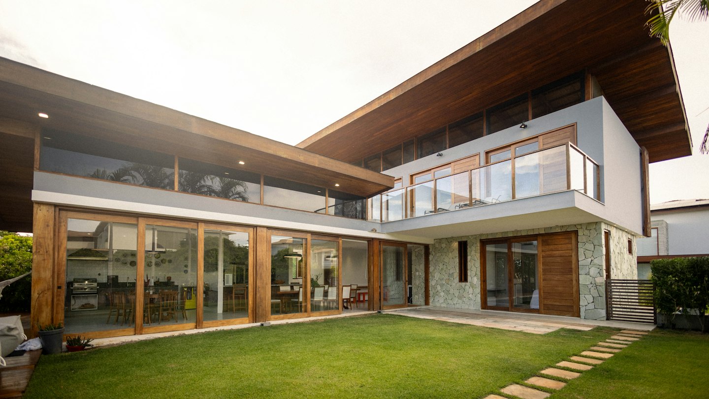 Modern house with glass doors and wood accents overlooking a lawn.